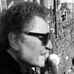 Black and White side on head shot of white male in his 50s. Wearing black glasses.