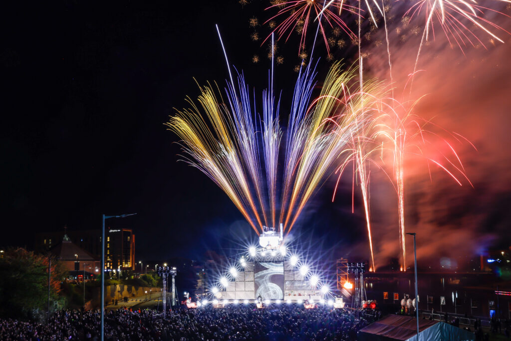 Finale of Ghost Train outdoor theatrical production. Train sits atop a 12 meter high scaffold stage. Bright lights, fireworks and a large audience.
