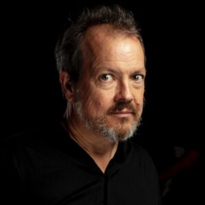 Head shot of white man in his 50s wearing a black smart shirt.